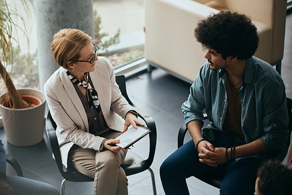 A young man meets with his therapist in a traditional talk therapy session